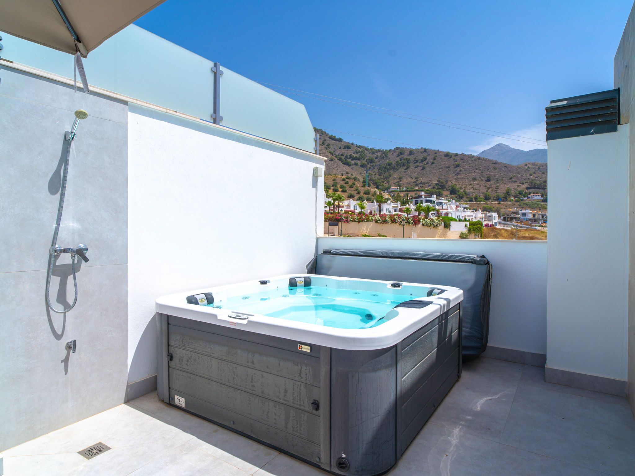 A hot tub on a balcony with a view of a hillside town.