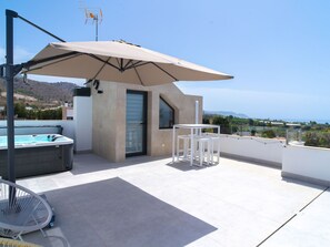 Eine Dachterrasse mit Whirlpool, Sitzgelegenheiten im Freien und Blick auf die Landschaft.