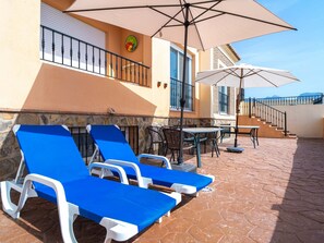 A terrace with sun loungers, a table, and chairs, and a staircase leading to an upper level. - Villa Punta Lara 15 by Casasol by Interhome (Nerja)