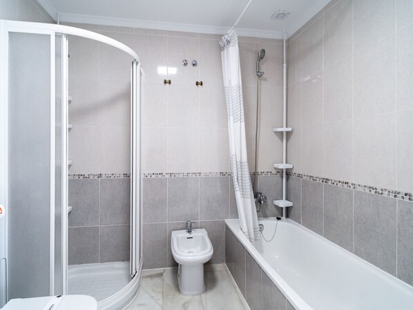 Ein Badezimmer mit Dusche, Toilette und Badewanne.