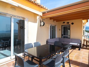 Eine sonnige Terrassengaststätte mit Esstisch, Stühlen und einer Couch.
