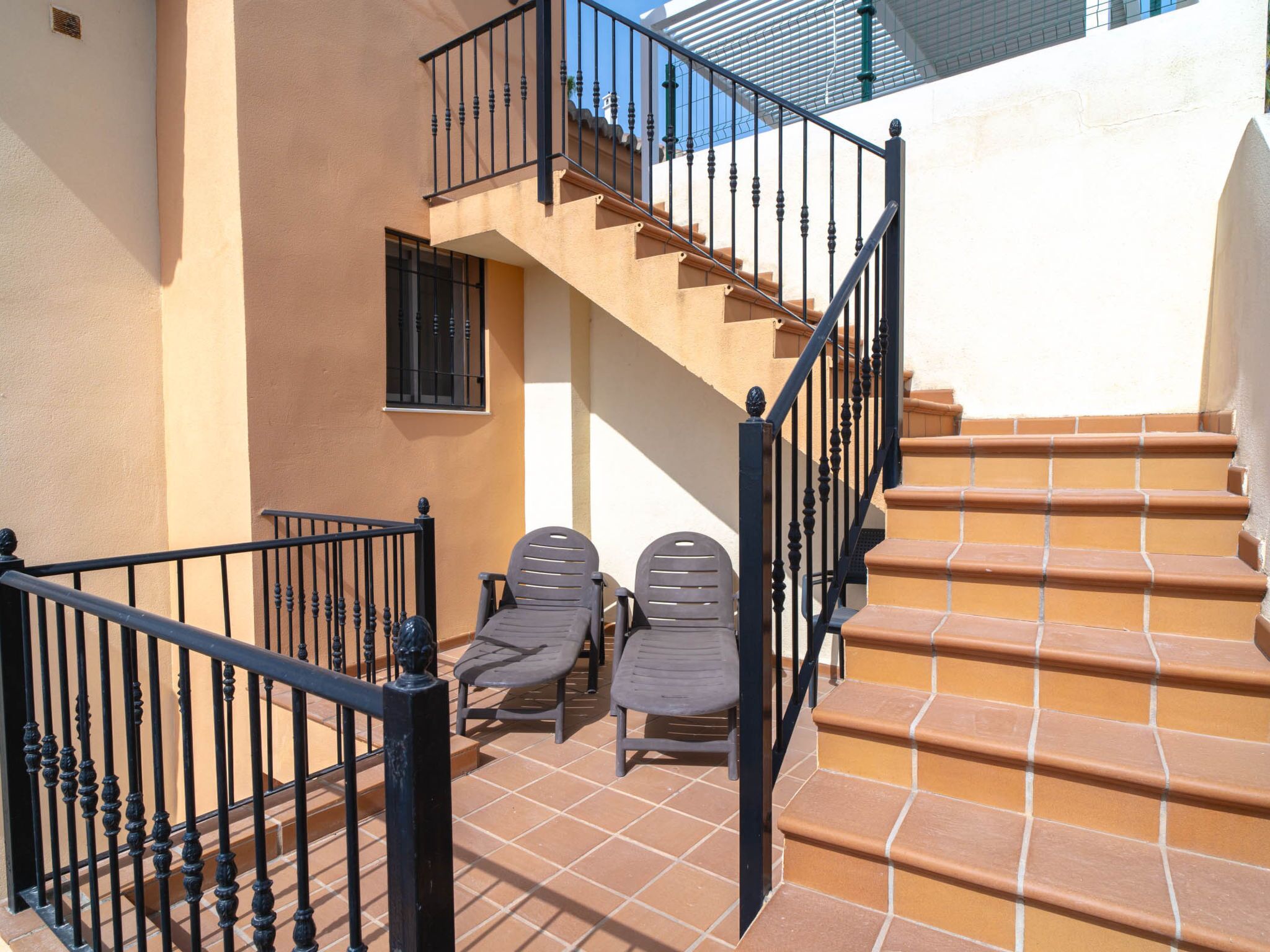 A staircase with a black railing leading to a second-floor balcony.