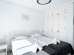 A white bedroom with a bed, two bedside tables, a wardrobe, and a framed picture on the wall. - Villa Punta Lara 15 by Casasol by Interhome (Nerja)