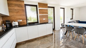 A modern kitchen with white cabinets, a black countertop, and a wooden accent wall.