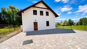 Ein zweistöckiges Haus mit gepflasterter Auffahrt und einem eingezäunten Garten.