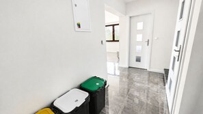 Un pasillo con un cubo de basura, una puerta y una ventana.