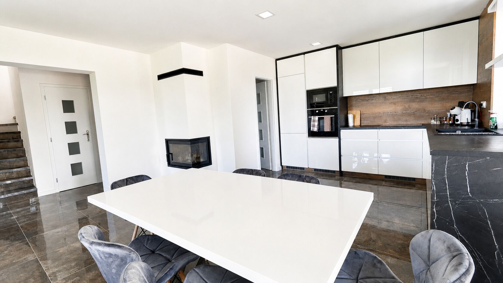 A modern kitchen with white cabinets, a black countertop, and a built-in oven.