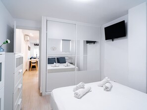 A modern hotel room with a bed, a TV mounted on the wall, and a bathroom visible through a sliding door. - Apartment  by Interhome (Nerja)
