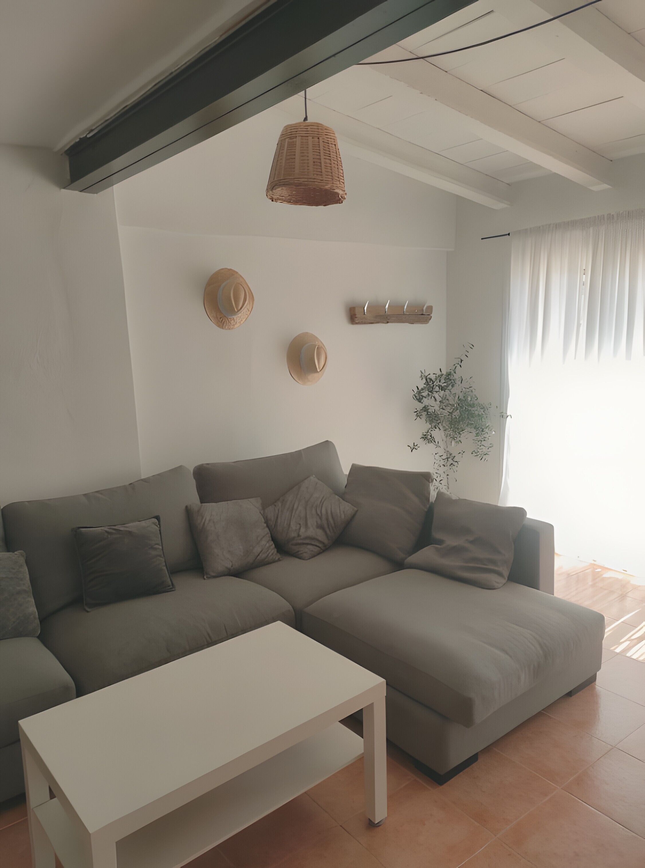 A modern living room with a sectional sofa, a white coffee table, and decorative wall art including hats and a plant.