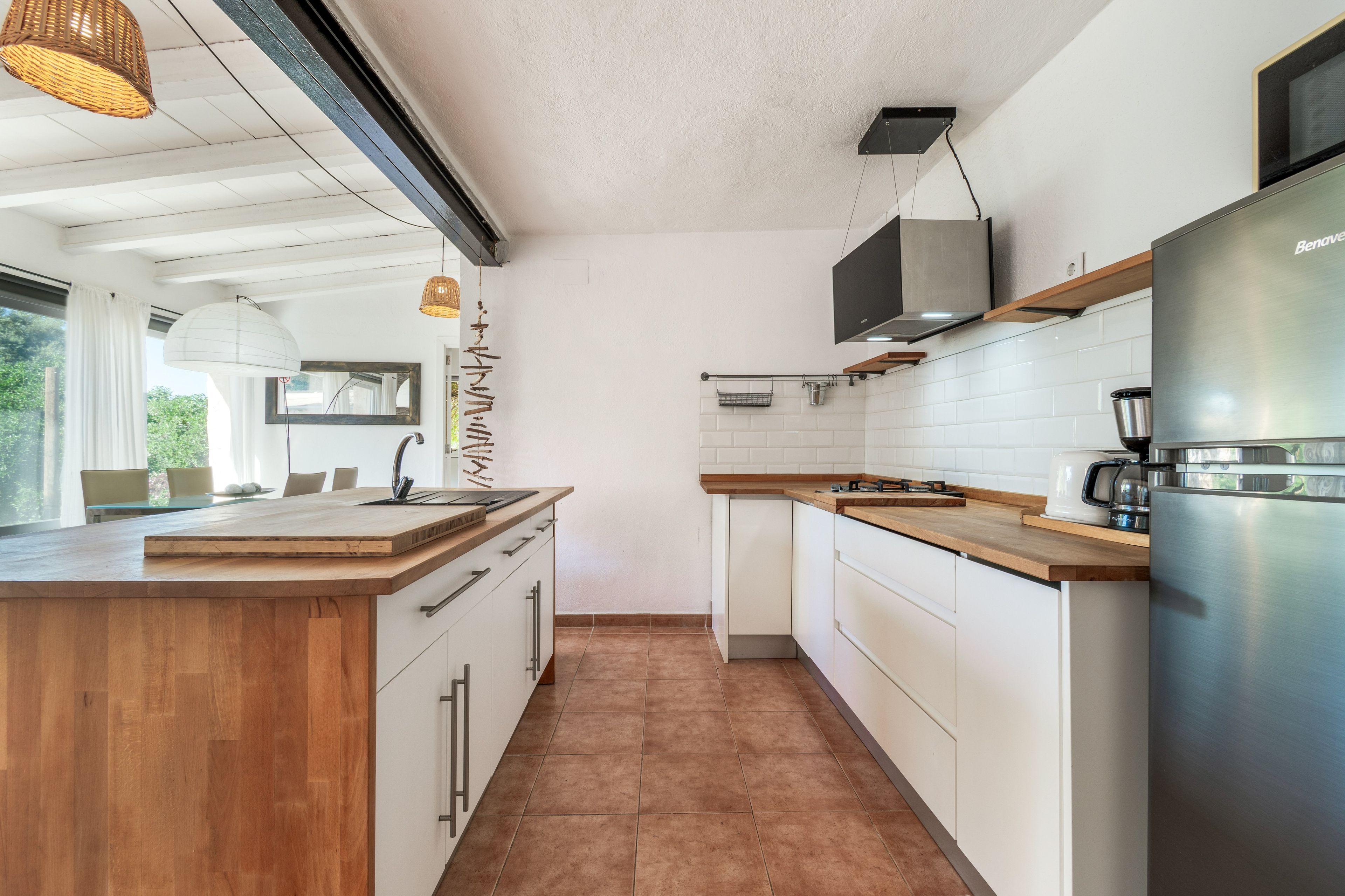 Una cocina moderna con armarios blancos, un refrigerador de acero inoxidable y una encimera de madera.