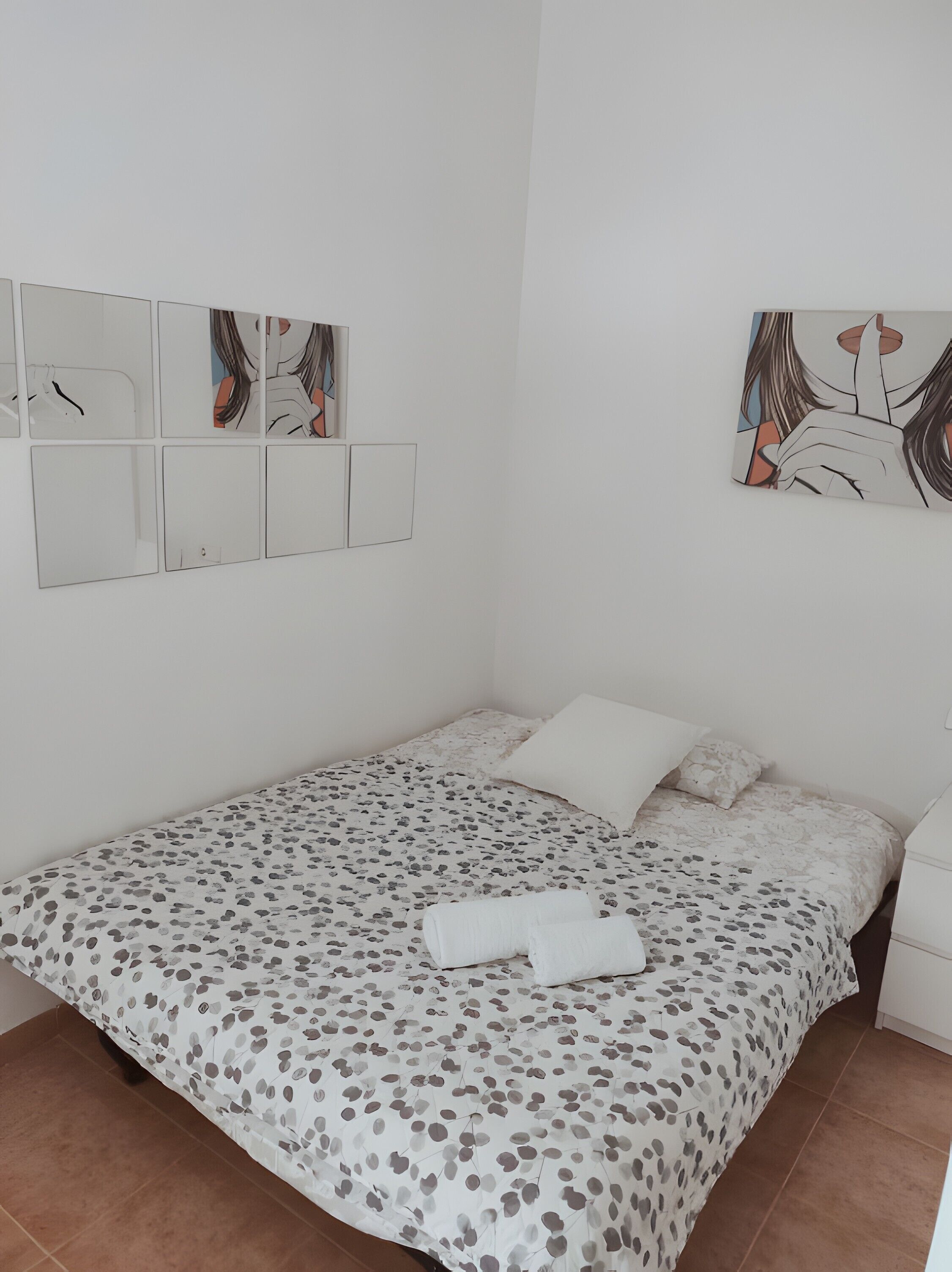 Un dormitorio con una cama, una mesita de noche y obras de arte en la pared.