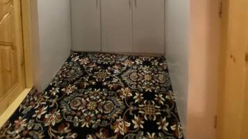 Quarto com carpete estampado, guarda-roupa de duas portas e uma luminária no teto.