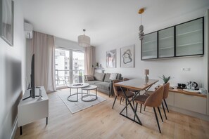 A modern living space with a dining area, sofa, and a large window with a view. - Kierbedzia Premium Apartament, Mokotów (Warszawa)