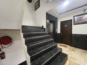 A staircase with black marble steps leading to an elevator. - Oly Hotel Ruhaan Near New Delhi Railway  (New Delhi)