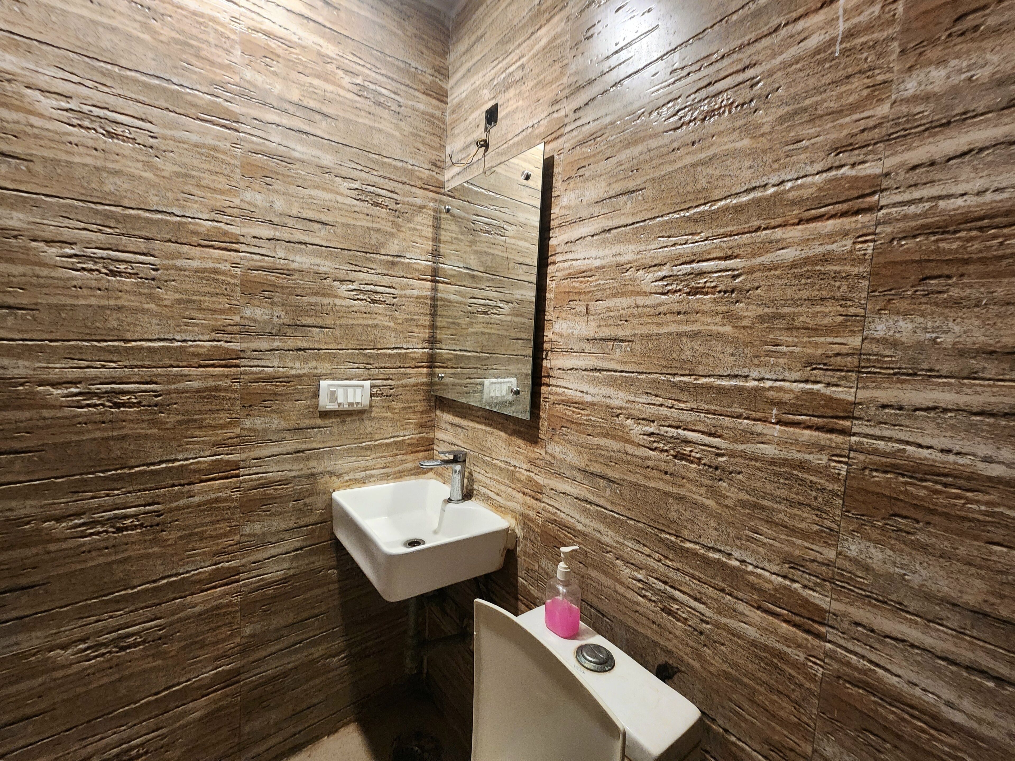 Un baño con lavamanos, espejo y dispensador de jabón.