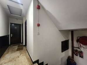 A corridor with a door labeled '101', a fire alarm, and fire extinguishers mounted on the wall. - Oly Hotel Ruhaan Near New Delhi Railway  (New Delhi)