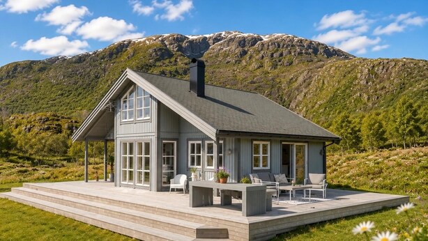 A modern house with a large deck, multiple windows, and a mountain backdrop. - Oceanview Cabin Sleeps 6 - Sauna - Private Terrace (Bø)