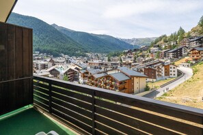 Un poble de muntanya amb edificis tradicionals, un camí sinuós i vistes a les muntanyes circumdants.
