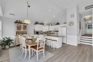 Une cuisine moderne avec des meubles blancs, un îlot central et des tabourets de bar.