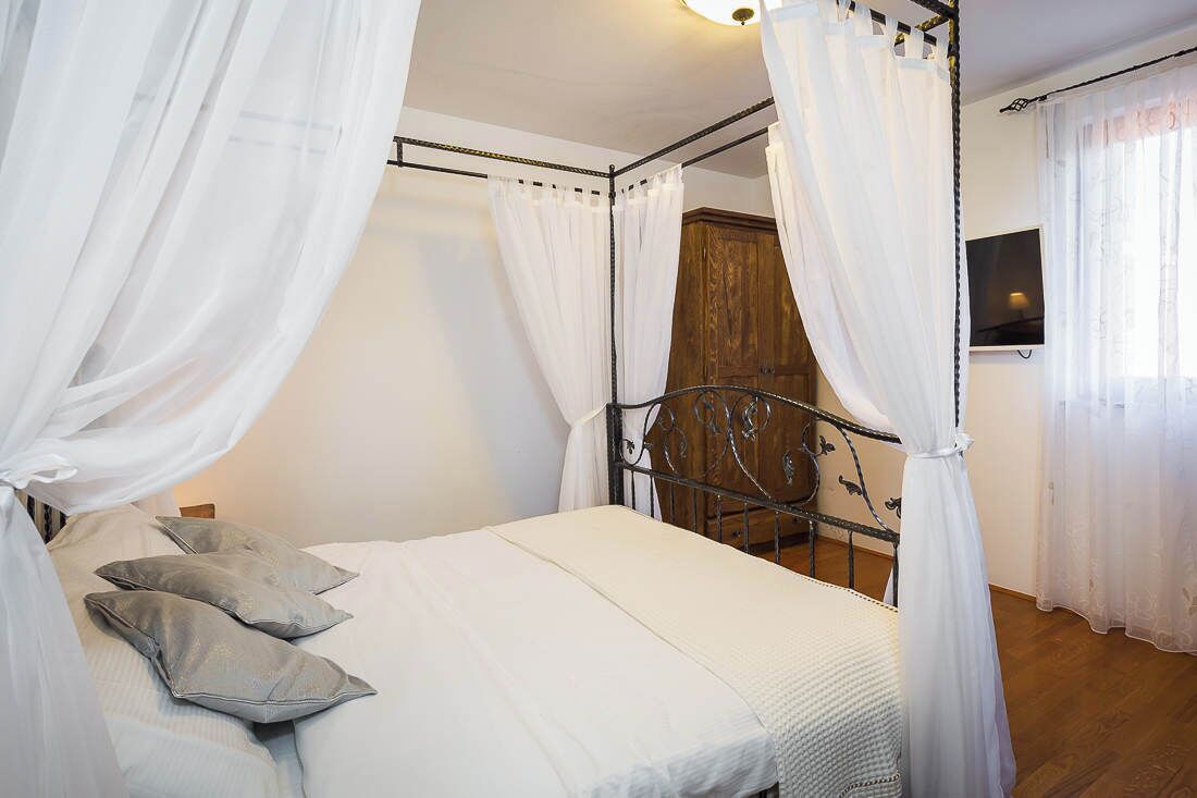 Une chambre à coucher avec un lit à baldaquin, des rideaux blancs et une armoire en bois.