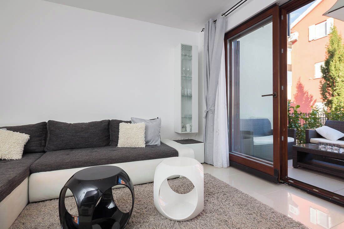 Uma sala de estar moderna com um sofá, uma mesa de centro e uma porta de vidro que dá para uma área de estar externa.