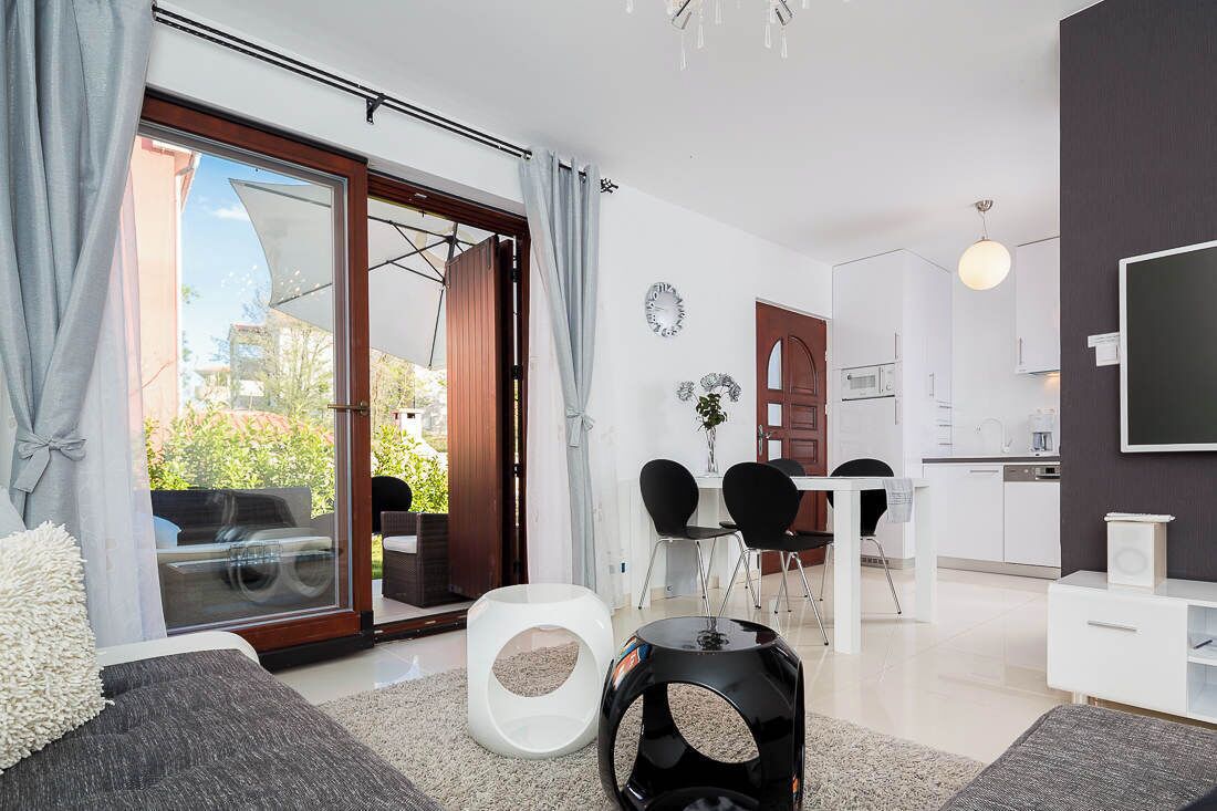 A modern living room with a sofa, a coffee table, and a dining area with chairs and a table.