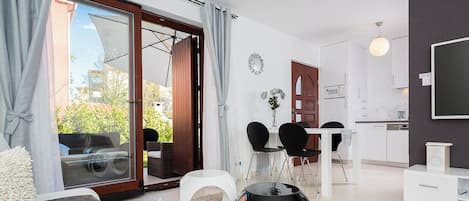 A modern living room with a sofa, a coffee table, and a dining area with chairs and a table.
