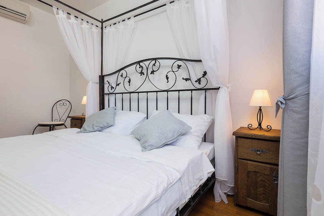 A bed with a metal headboard, white bedding, and two nightstands with lamps.
