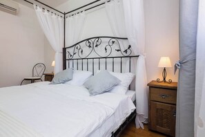 Ein Bett mit Metallkopfteil, weißer Bettwäsche und zwei Nachttischen mit Lampen.