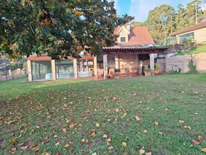 A house with a covered patio, a grassy yard, and a stone wall.