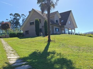 A two-story house with a sloped roof, a well-maintained lawn, and a stone pathway leading to the entrance.