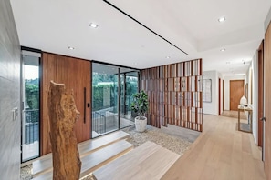 Un intérieur moderne avec un plancher en bois, une grande porte vitrée donnant sur un balcon et une plante en pot.