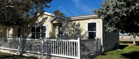 A single-story house with a white picket fence, a covered porch, and a clear blue sky.
