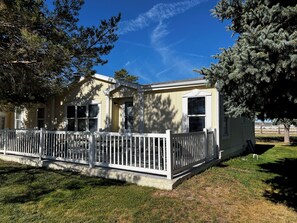 A single-story house with a white picket fence, a covered porch, and a clear blue sky. - Pines Peaks Retreat - 3 bedroom 2 bath, sleeps 8 - Gateway to Southern Utah (Cedar City)