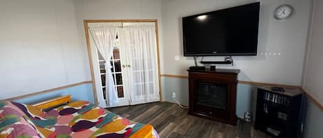 Un dormitorio con una cama, televisión, reloj y estantería.