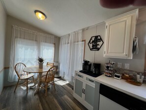 A kitchen with a dining table, chairs, a coffee station, and cabinets. - Pines Peaks Retreat - 3 bedroom 2 bath, sleeps 8 - Gateway to Southern Utah (Cedar City)
