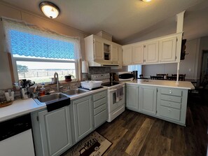 A kitchen with white cabinets, a built-in oven, and a window overlooking a grassy area. - Pines Peaks Retreat - 3 bedroom 2 bath, sleeps 8 - Gateway to Southern Utah (Cedar City)