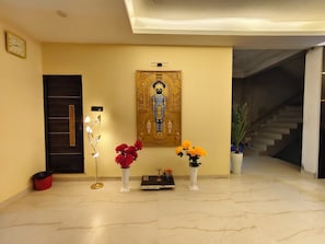 Un pasillo con una puerta, un panel decorativo en la pared y dos jarrones con flores.