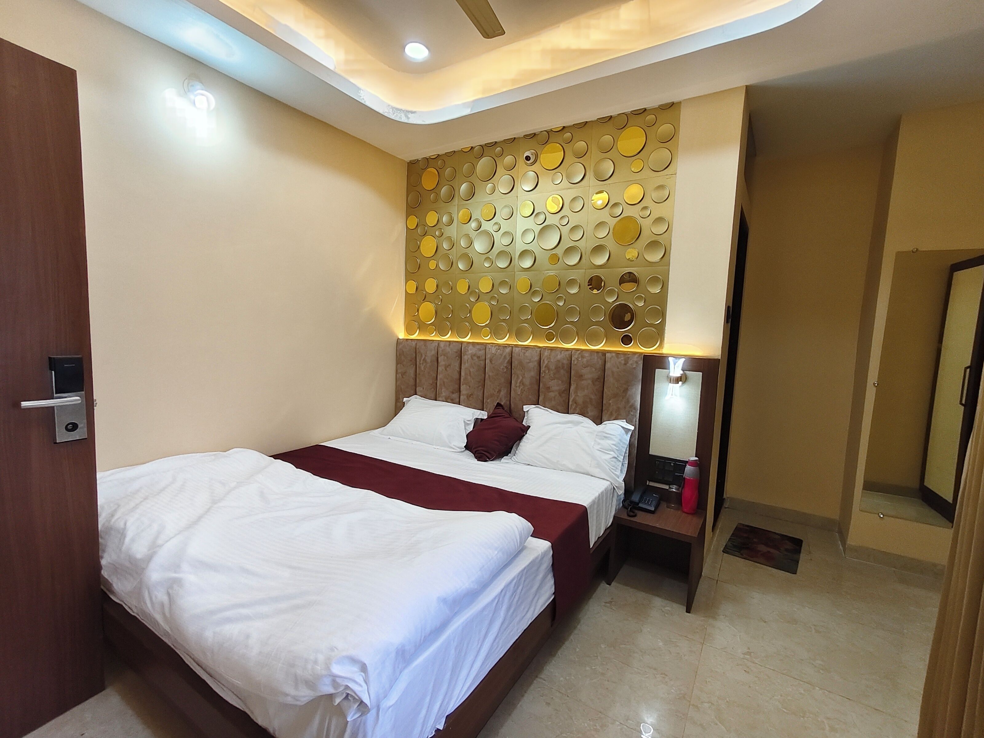 A hotel room with a bed, bedside table, and a wall with circular patterns.