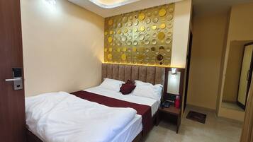 A hotel room with a bed, bedside table, and a wall with circular patterns.