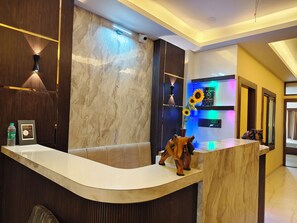 A reception area with a curved counter, a sofa, a wall-mounted light fixture, and a framed informational sign.