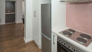 Eine Küche mit einem Edelstahl-Kühlschrank, einem Herd mit vier Kochfeldern und einer gefliesten Spritzschutzwand.
