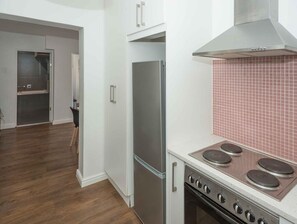 A kitchen with a stainless steel refrigerator, a stove with four burners, and a tiled backsplash. - Stylish Gardens Apt Views, Steps from Kloof Street (Cape Town)