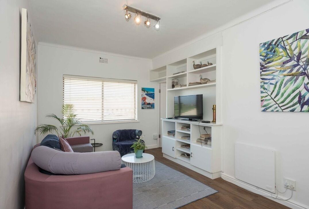 A living room with a sofa, a television, a bookshelf, and a plant.