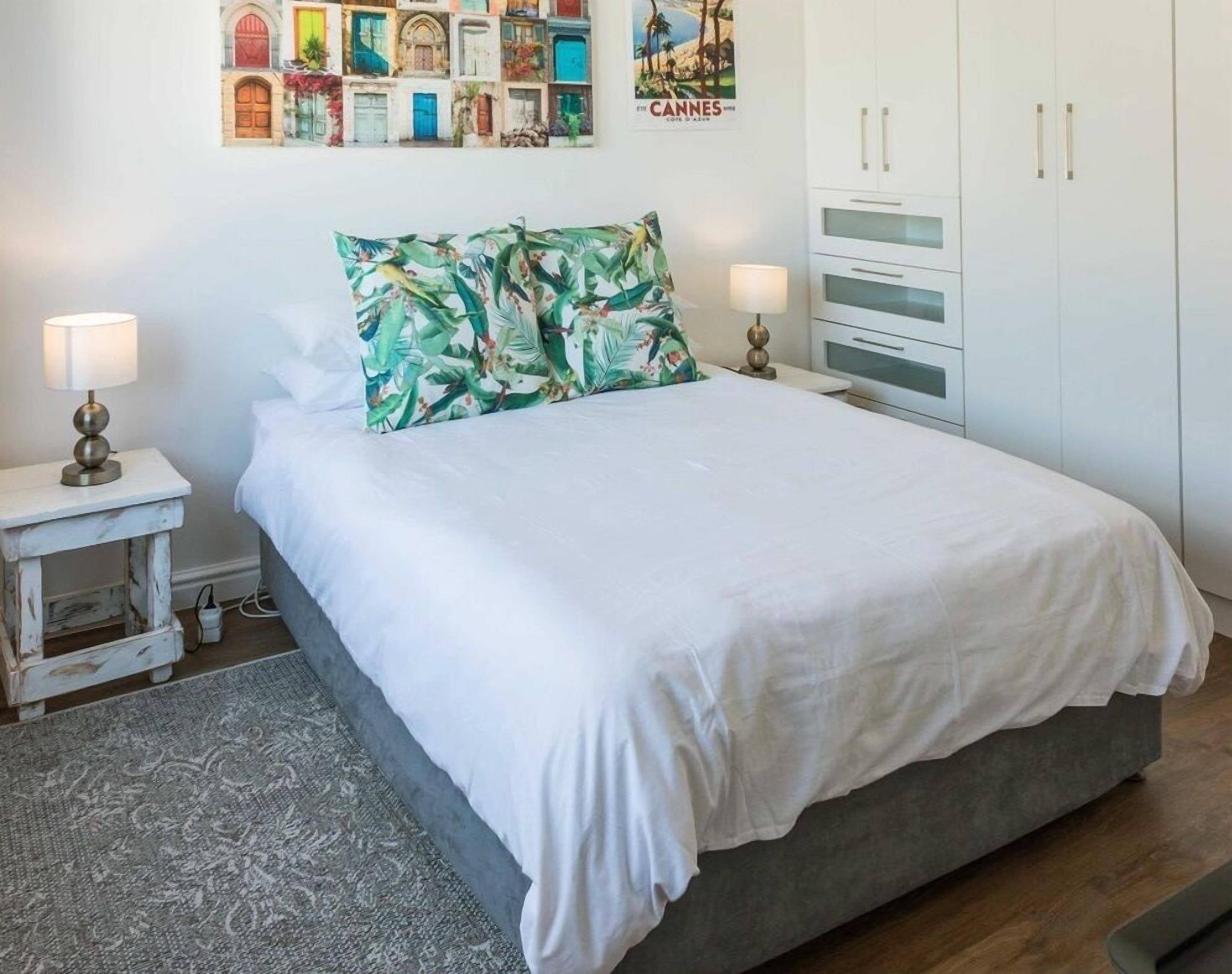 A bedroom with a bed, nightstands, a lamp, a wardrobe, and a wall with a poster.
