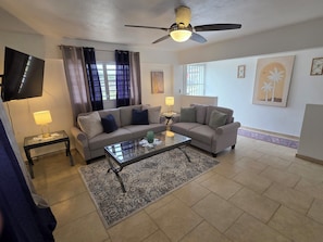 A living room with two sofas, a coffee table, a TV, and a ceiling fan.