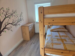 A bunk bed with a wooden headboard, a dresser with drawers, a radiator, and a wall decal of a tree. - Lovingly renovated farmhouse for 2–8 people. 3 km from Bayernpark. (Reisbach)
