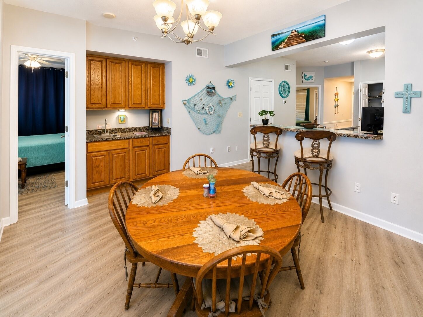 A dining area with a wooden table and chairs, a kitchen with wooden cabinets, and a living area with a blue curtain.