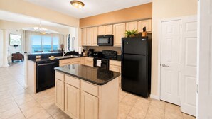Uma cozinha moderna com ilha central, micro-ondas, frigorífico e lava-louças.