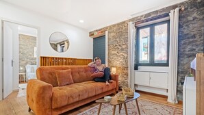 A living room with a sofa, a small table, a mirror, and a stone wall. - Stone House Rochinha by Homie (Funchal)